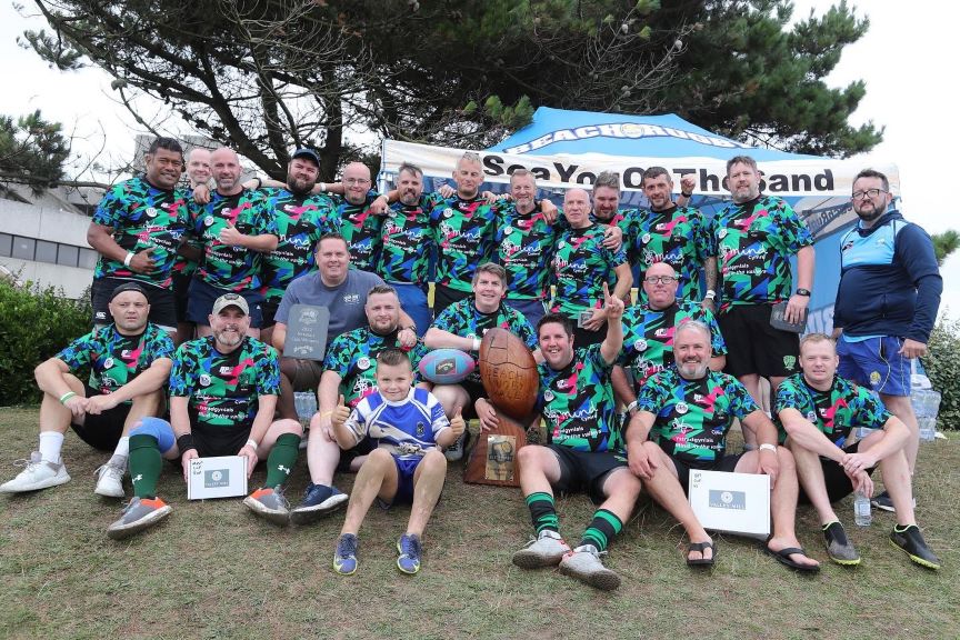 The photograph shows a group shot of a walking rugby team